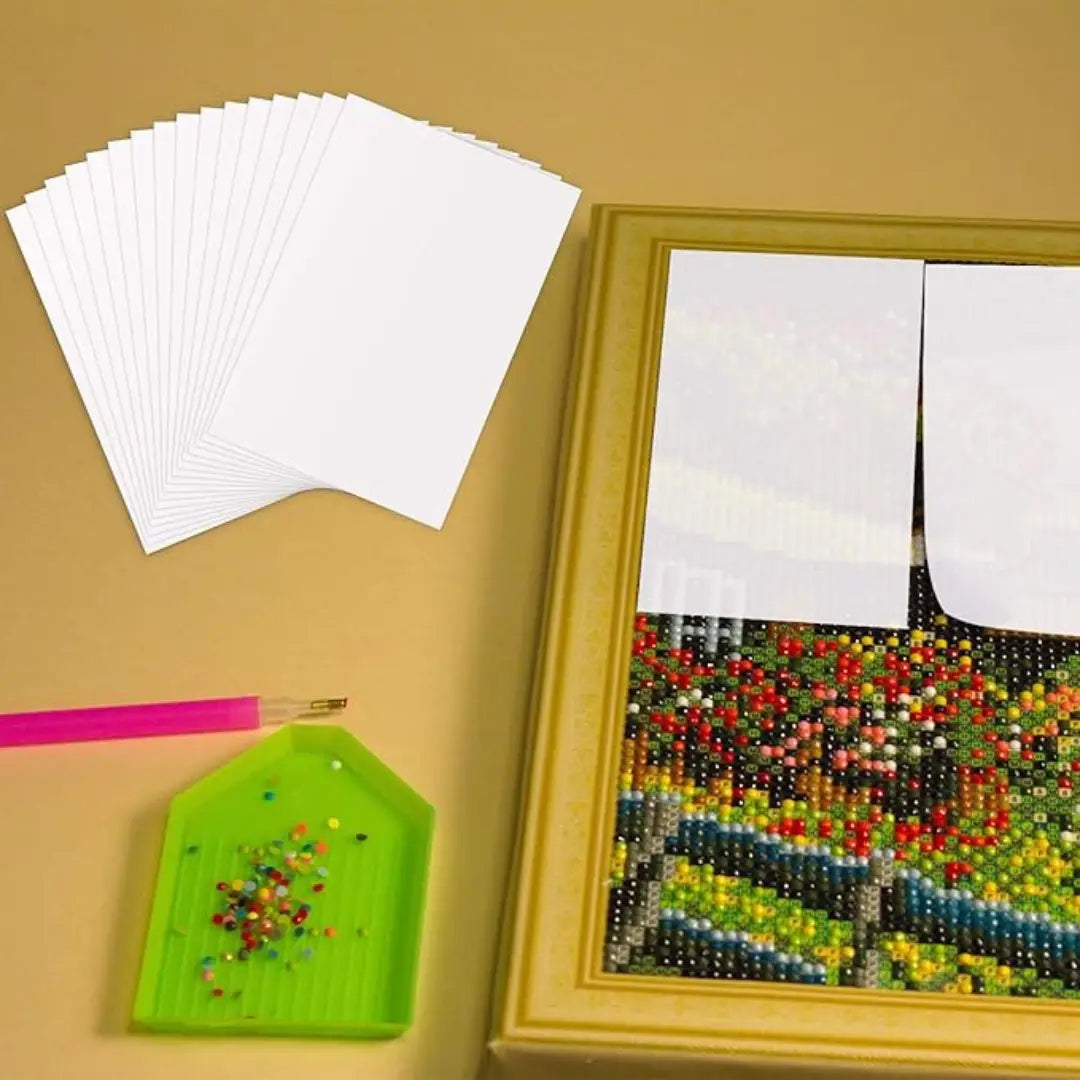 Afdekstickers gebruikt op deels voltooide diamond painting met gereedschap en kralen ernaast.