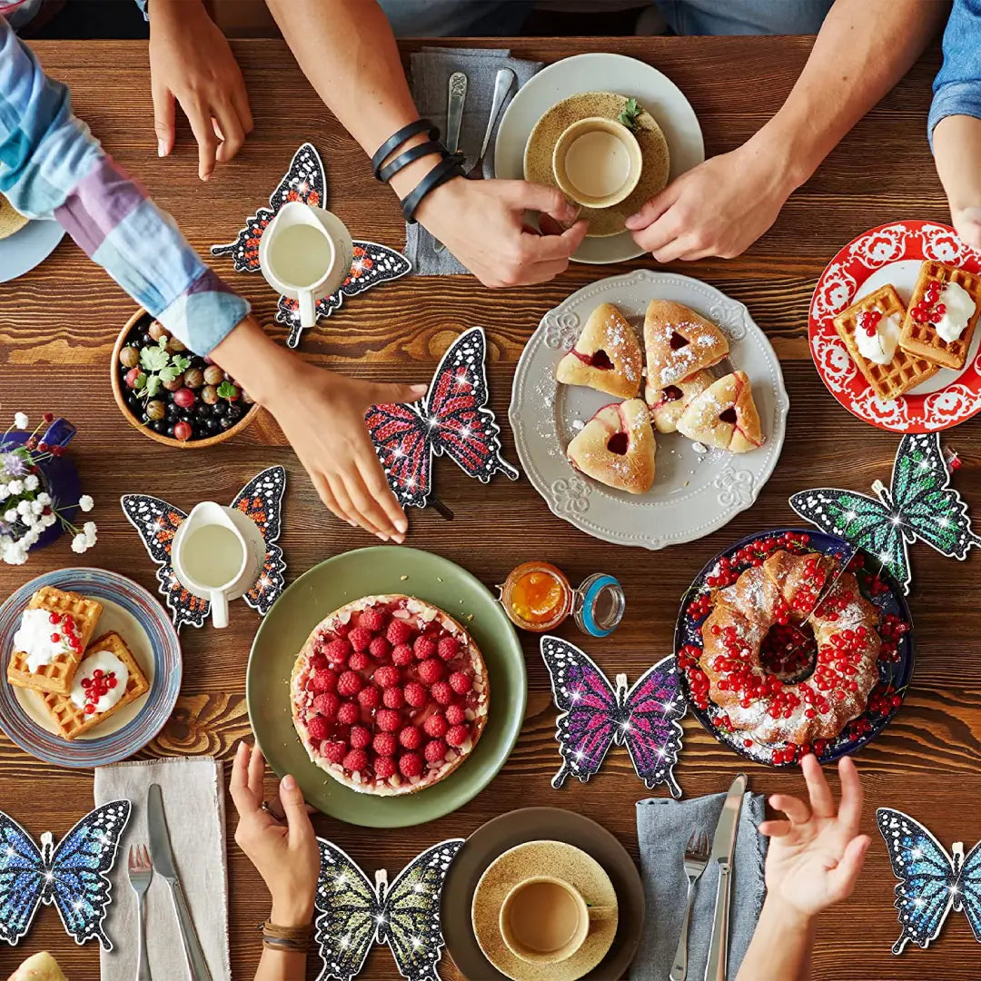 Diverse brunchgerechten op een houten tafel, omringd door vlinder diamond painting onderzetters in diverse kleuren.