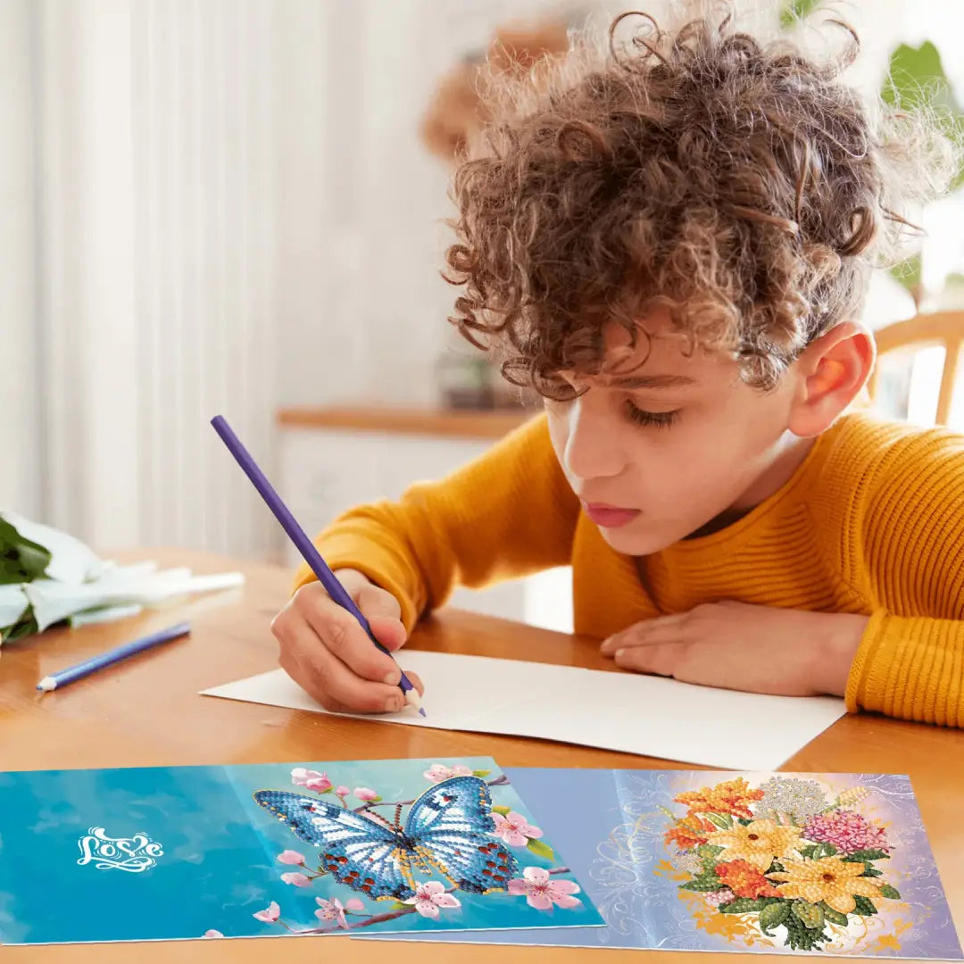 Jongen werkt geconcentreerd aan diamond painting kaarten met vlinders en bloemen, stimulerend voor creativiteit en fijne motoriek.