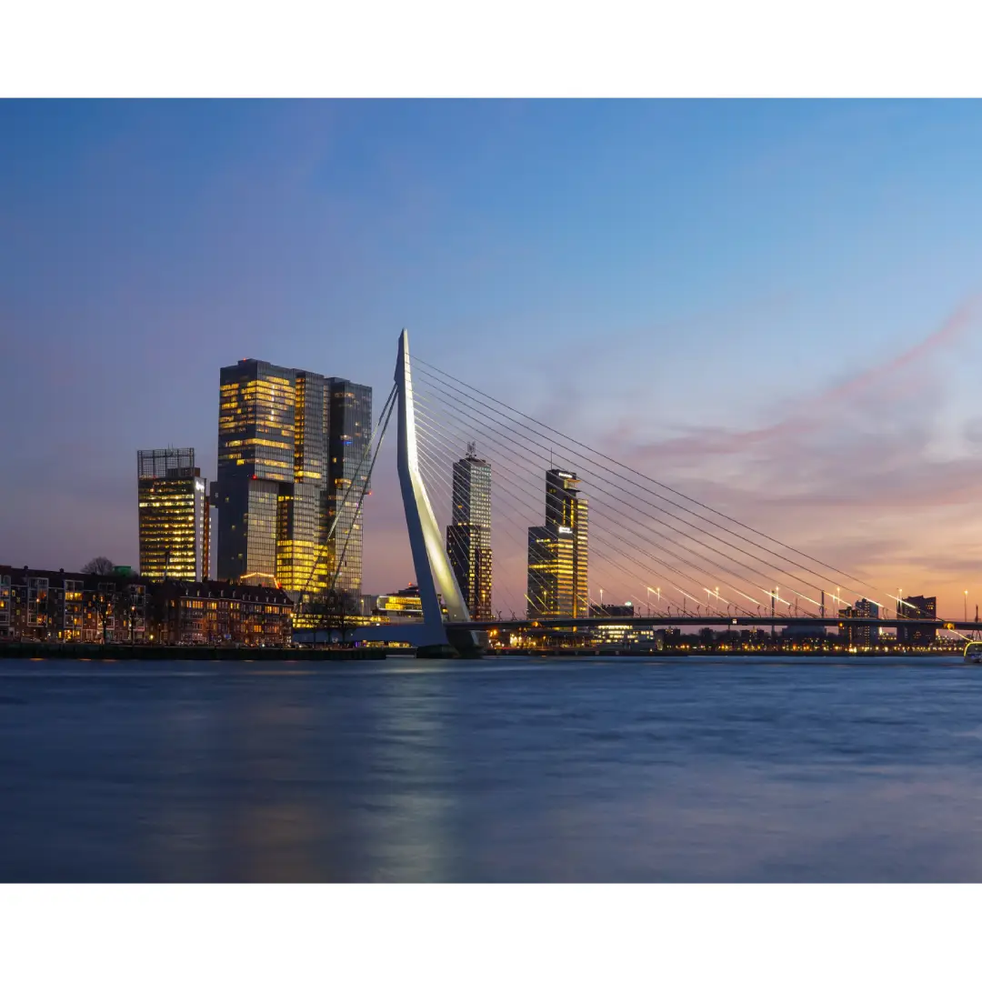 Diamond painting voorbeeld van de Rotterdamse Erasmusbrug bij zonsondergang met verlichte gebouwen op de achtergrond.