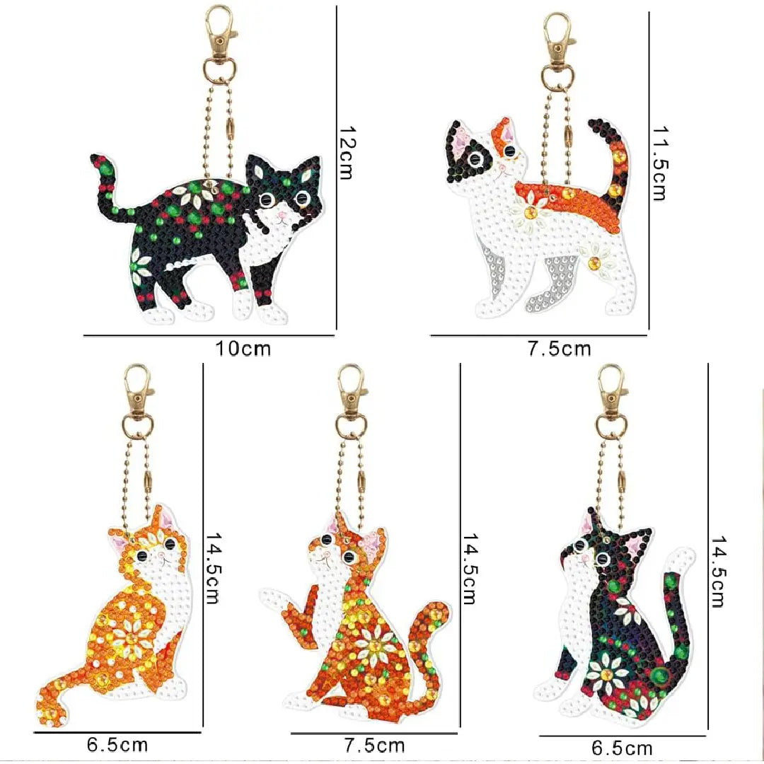 Verscheidenheid aan diamond painting sleutelhangers in de vorm van katten met verschillende kleurrijke patronen, afmetingen variërend van 6.5 tot 12 cm.